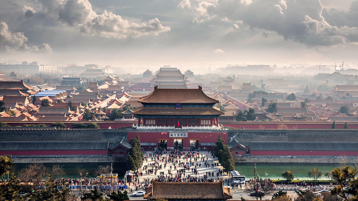 The Forbidden City in Beijing viewed from above with imperial rooftops and historic palace buildings stretching across the city.